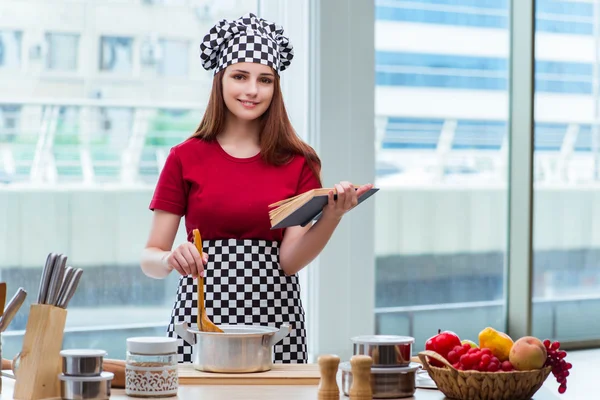 Young housewife referring to recipe book — Stock Photo, Image