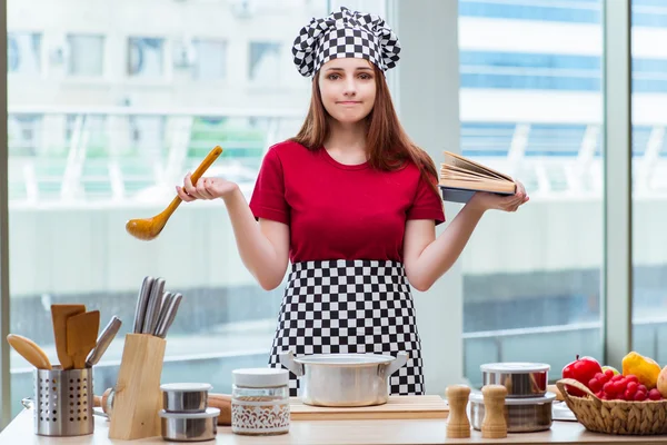 Young housewife referring to recipe book — Stock Photo, Image
