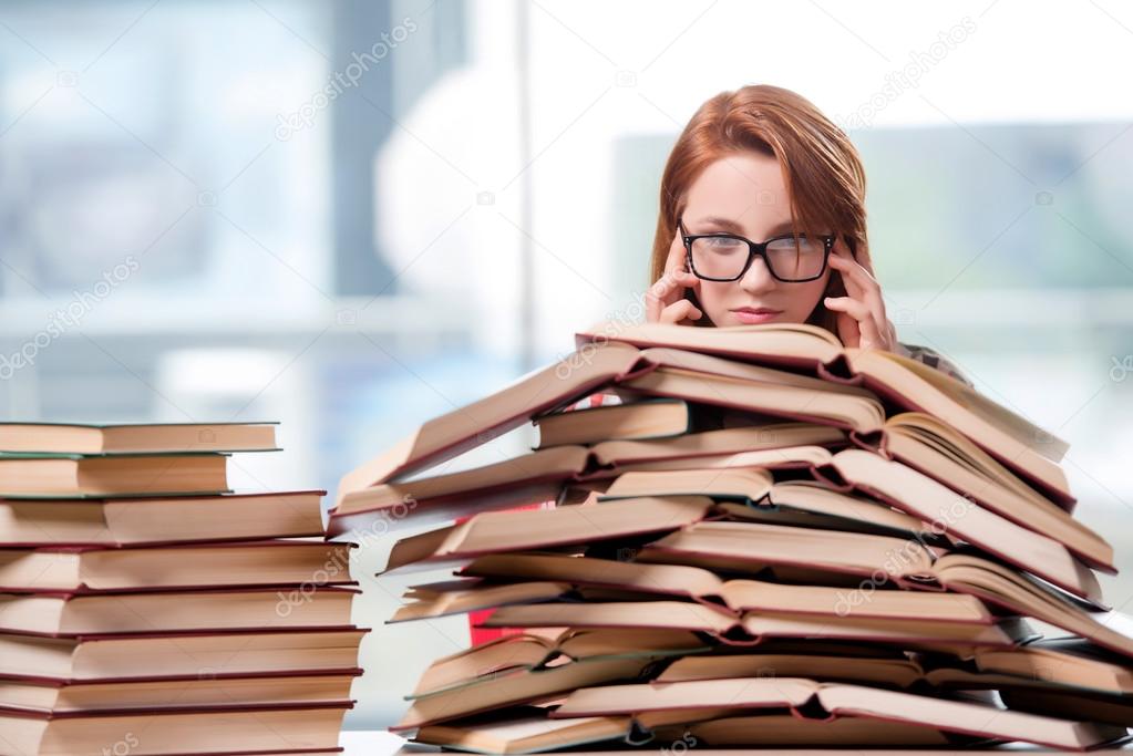 Student mit Stapeln von Büchern, die sich auf Prüfungen vorbereiten
