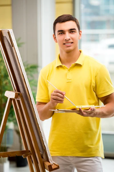 Jonge mannelijke kunstenaar tekening foto 's in heldere studio — Stockfoto