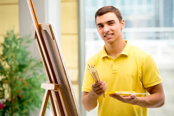 Jovem artista masculino desenho de imagens em estúdio brilhante — Fotografia de Stock