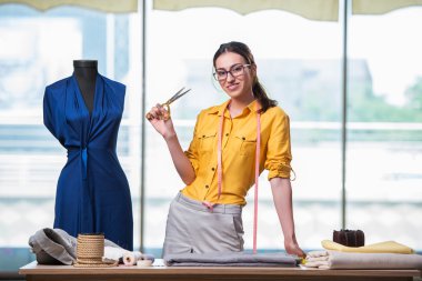 Kadın terzi yeni elbiseler üzerinde çalışıyor.