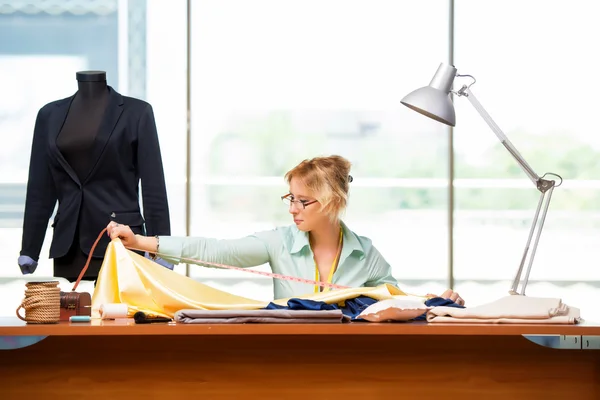 Mulher alfaiate trabalhando em roupas novas — Fotografia de Stock