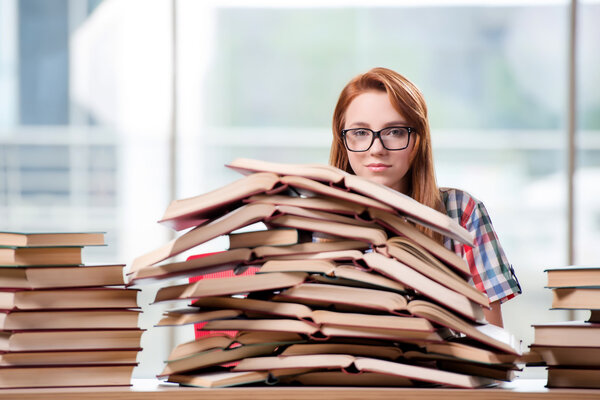 Студент с пачками книг, готовящихся к экзаменам