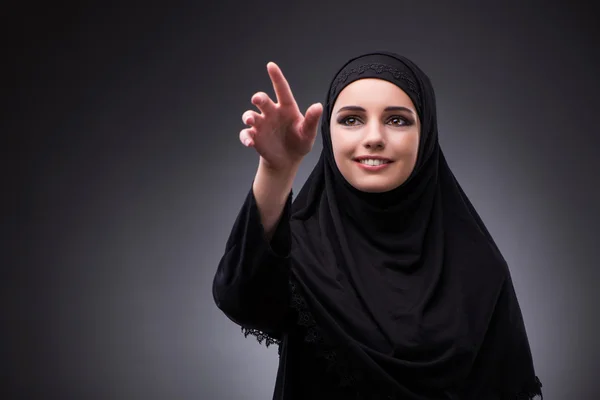 Muslimsk kvinna i svart klänning mot mörk bakgrund — Stockfoto