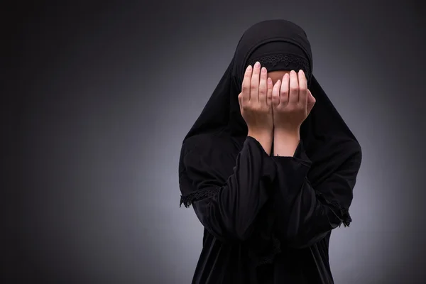 Muslimische Frau in schwarzem Kleid vor dunklem Hintergrund — Stockfoto