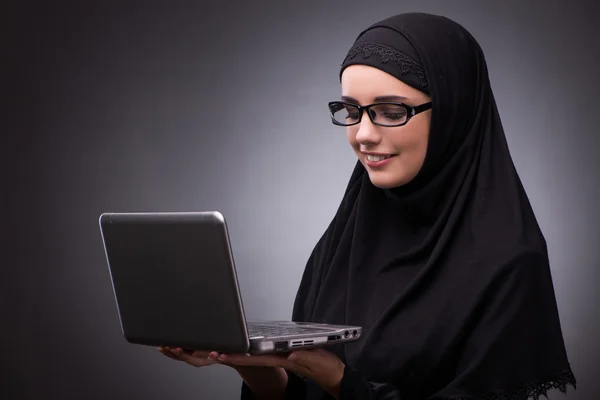 Moslimvrouw in zwarte jurk tegen de donkere achtergrond — Stockfoto