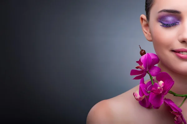 Νεαρή γυναίκα στην έννοια της ομορφιάς με ορχιδέα λουλούδι — Φωτογραφία Αρχείου