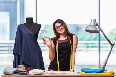 Kadın terzi yeni elbiseler üzerinde çalışıyor.