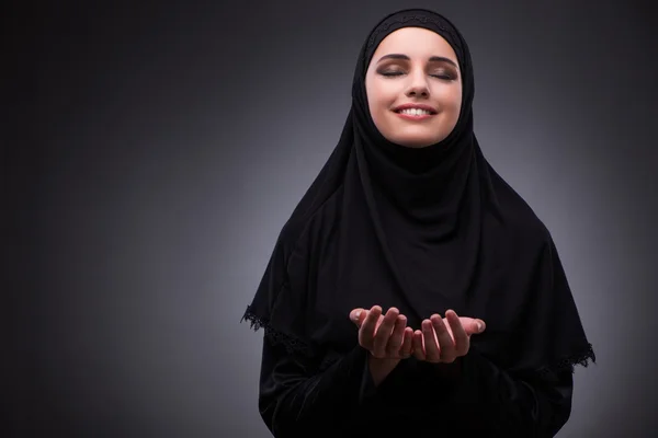 Donna musulmana in abito nero contro sfondo scuro — Foto Stock