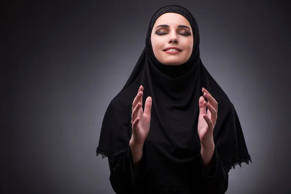 Muslimische Frau in schwarzem Kleid vor dunklem Hintergrund — Stockfoto