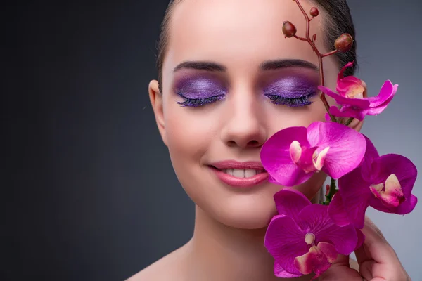 Mujer joven en concepto de belleza con flor de orquídea — Foto de Stock