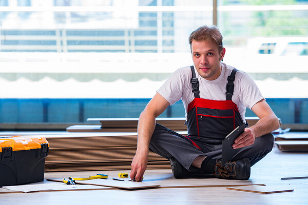 Man laying laminate flooring in construction concept