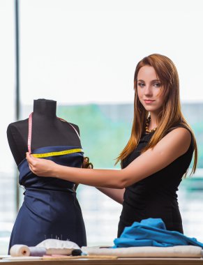 Kadın terzi yeni elbiseler üzerinde çalışıyor.