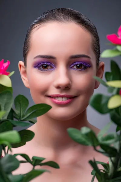 Mujer joven con flores en concepto de belleza — Foto de Stock