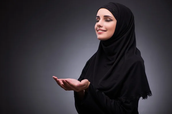 Muslimische Frau in schwarzem Kleid vor dunklem Hintergrund — Stockfoto