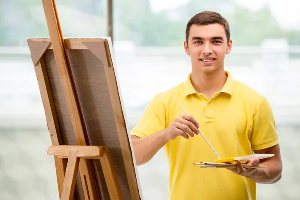 Jonge mannelijke kunstenaar tekening foto 's in heldere studio — Stockfoto