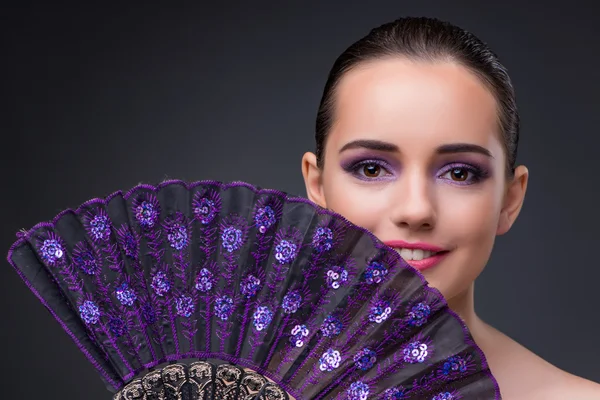 Nice woman with fan against gray background