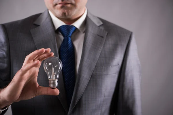 Businessman holding light bulb in creativity concept — Stock Photo, Image