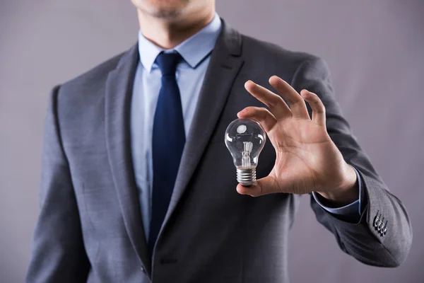 Businessman holding light bulb in creativity concept — Stock Photo, Image