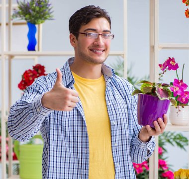Çiçekçide çalışan genç bir adam.