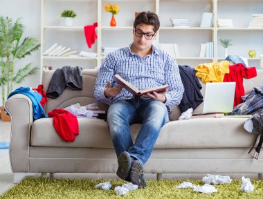 Genç adam dağınık bir odada çalışıyor.