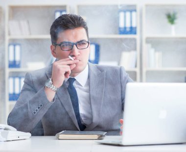 İşadamı ofisinde sigara içiyor.