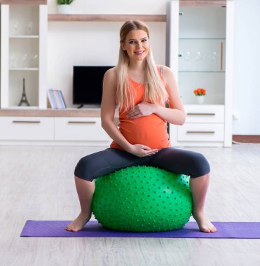 Evde doğum egzersizi yapmaya hazırlanan genç bir kadın.