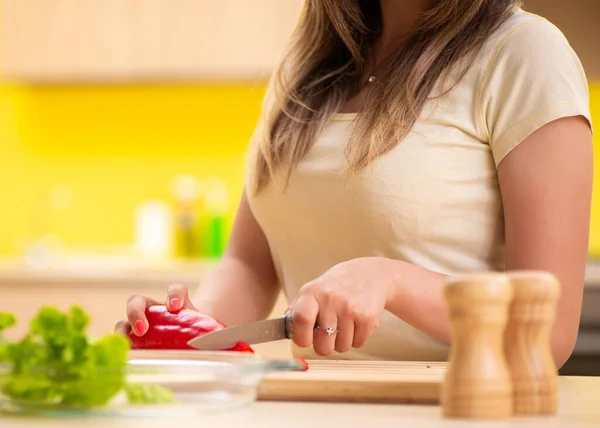 Молодая женщина готовит салат дома на кухне — стоковое фото