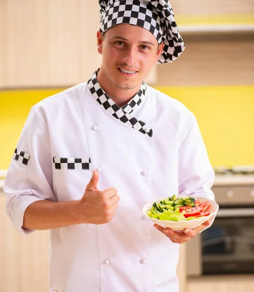 Jonge professionele kok bereidt salade in de keuken — Stockfoto