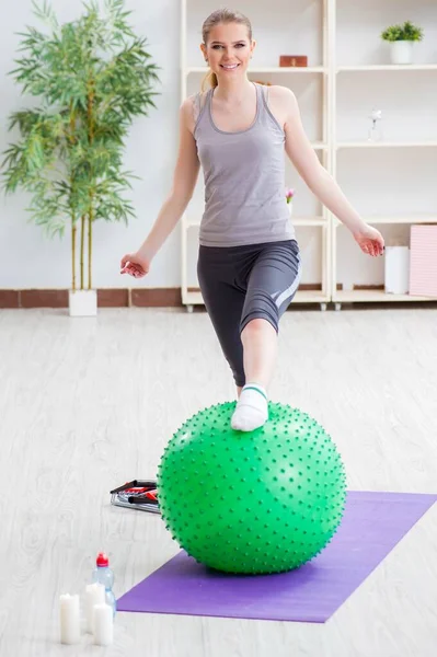 헬스클럽에서 안정된 공을 가지고 운동하는 젊은 여자 — 스톡 사진
