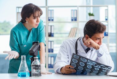 İki doktor hastanede röntgen görüntüsünü tartışıyor.