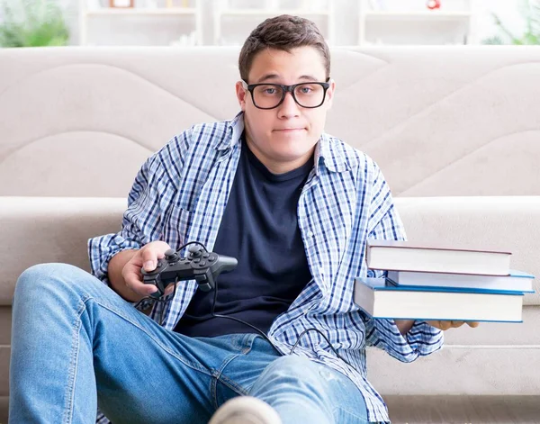 Joven estudiante tratando de equilibrar el estudio y jugar juegos —  Fotos de Stock