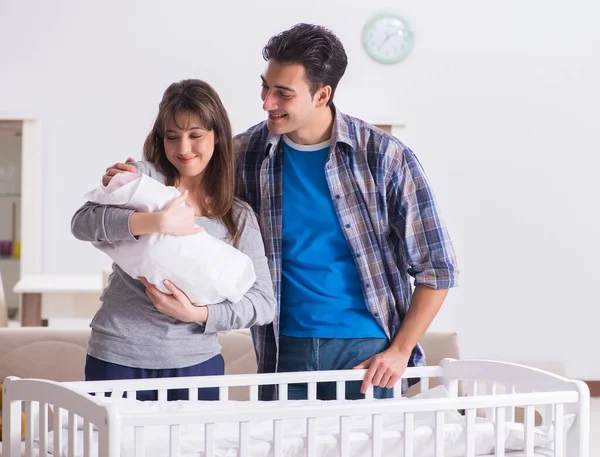 Padres jóvenes con su bebé recién nacido cerca de la cuna — Foto de Stock