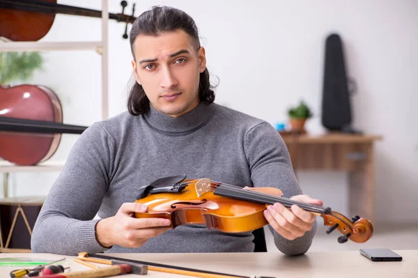 Young male repairman repairing violin