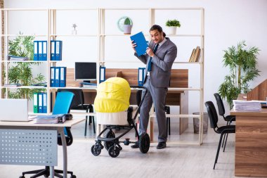 İş yerinde yeni doğan bebeğe bakan genç bir erkek işçi.