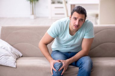 Evde acı çeken yaralı genç adam.