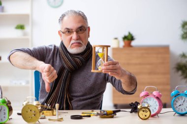 Atölyede çalışan yaşlı bir erkek saatçi.