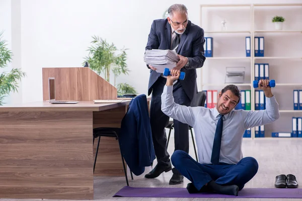 Dois funcionários fazendo exercícios físicos no local de trabalho — Fotografia de Stock