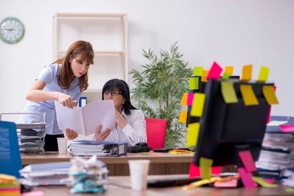 Две женщины-сотрудницы и чрезмерная работа в офисе — стоковое фото
