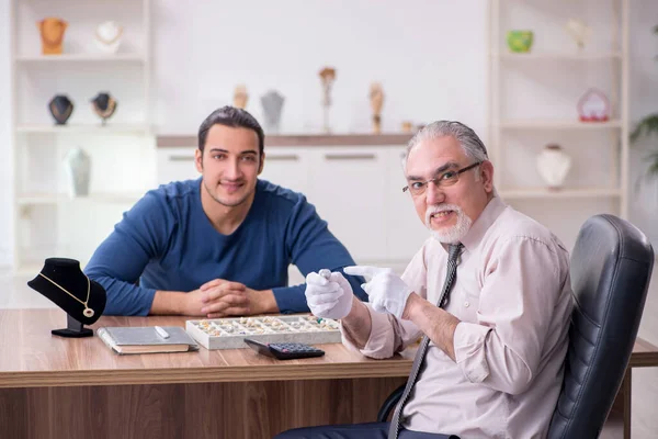 Joven visitando viejo joyero masculino — Foto de Stock