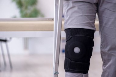 Koltuk değnekleriyle yaralı genç bir adam.