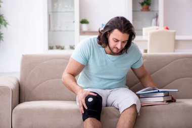 Genç bacak yaralı öğrenci evde çalışıyor.