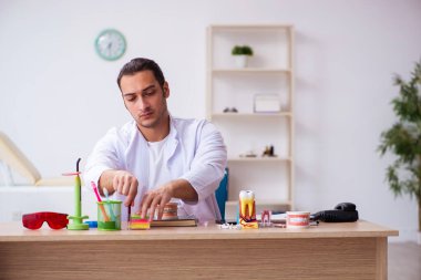 Klinikte çalışan genç erkek dişçi.