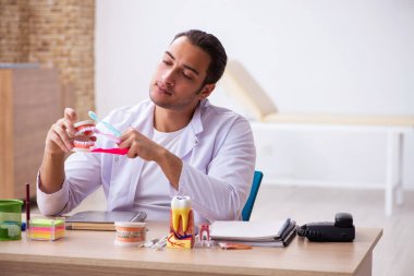 Klinikte çalışan genç erkek dişçi.