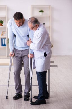 Genç bacağı yaralı adam yaşlı doktor osteopath 'ı ziyaret ediyor.