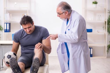 Genç yaralı futbolcu yaşlı doktor travmatoloğu ziyaret ediyor.