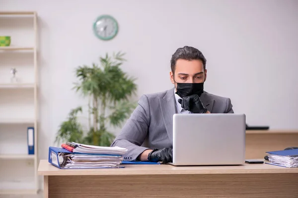 Young male employee in the office during pandemic disease — Stock Photo, Image