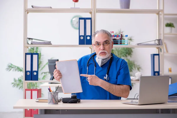 Klinikte çalışan yaşlı erkek doktor. — Stok fotoğraf