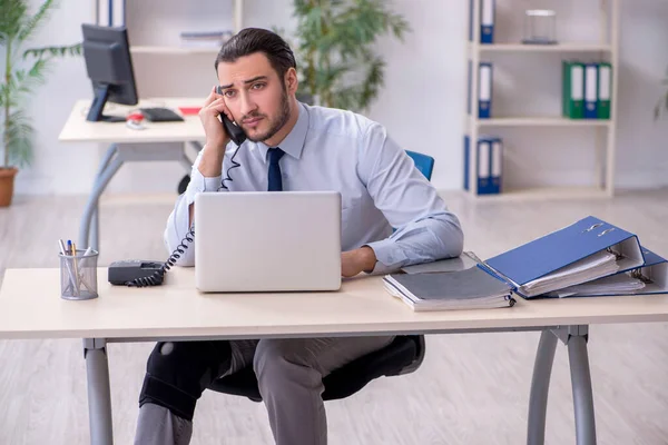 Giovane dipendente infortunato alla gamba che lavora in ufficio — Foto Stock